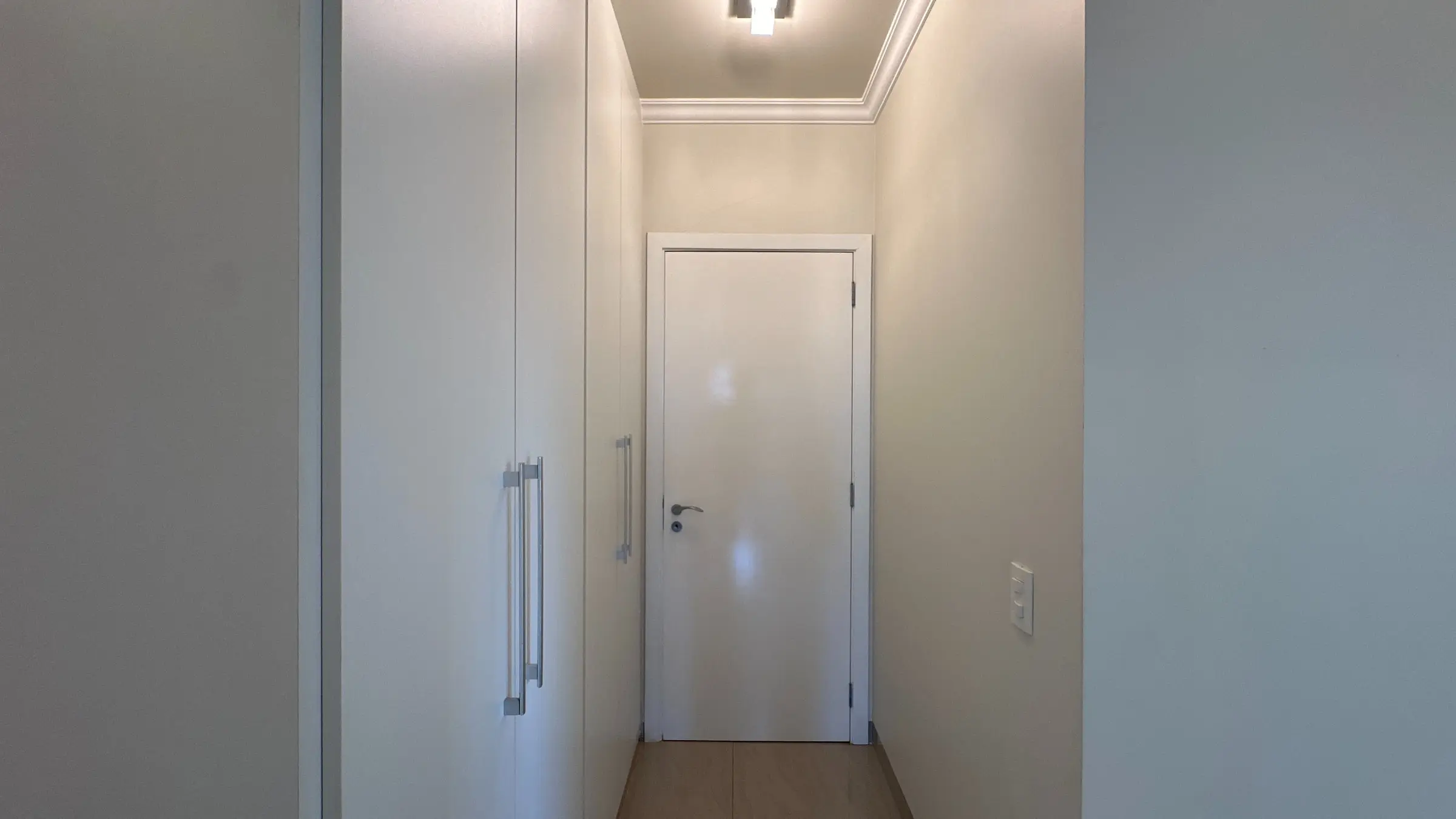 Corredor interno do apartamento com portas e armários embutidos