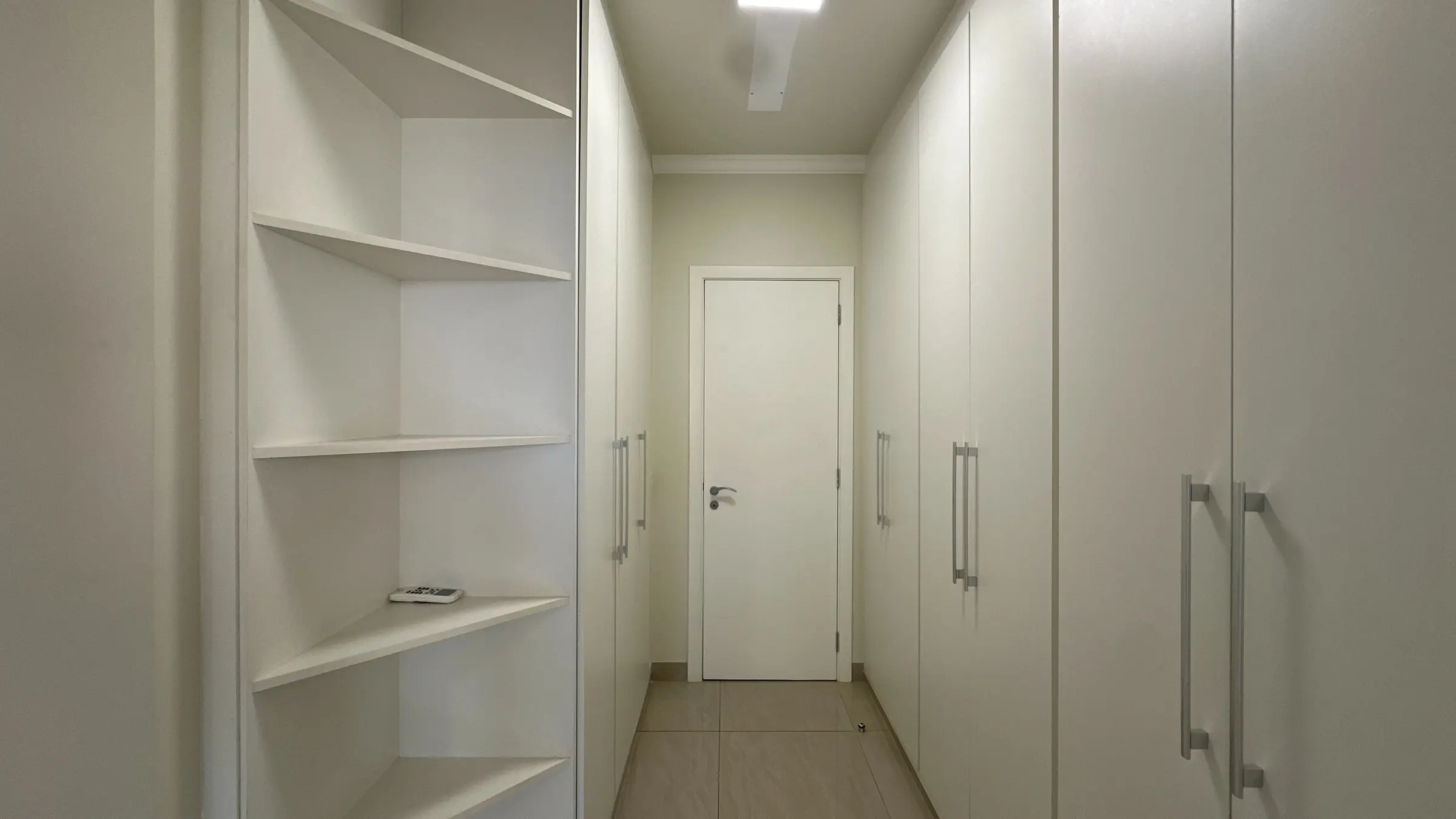 Closet do apartamento com prateleiras abertas e marcenaria branca