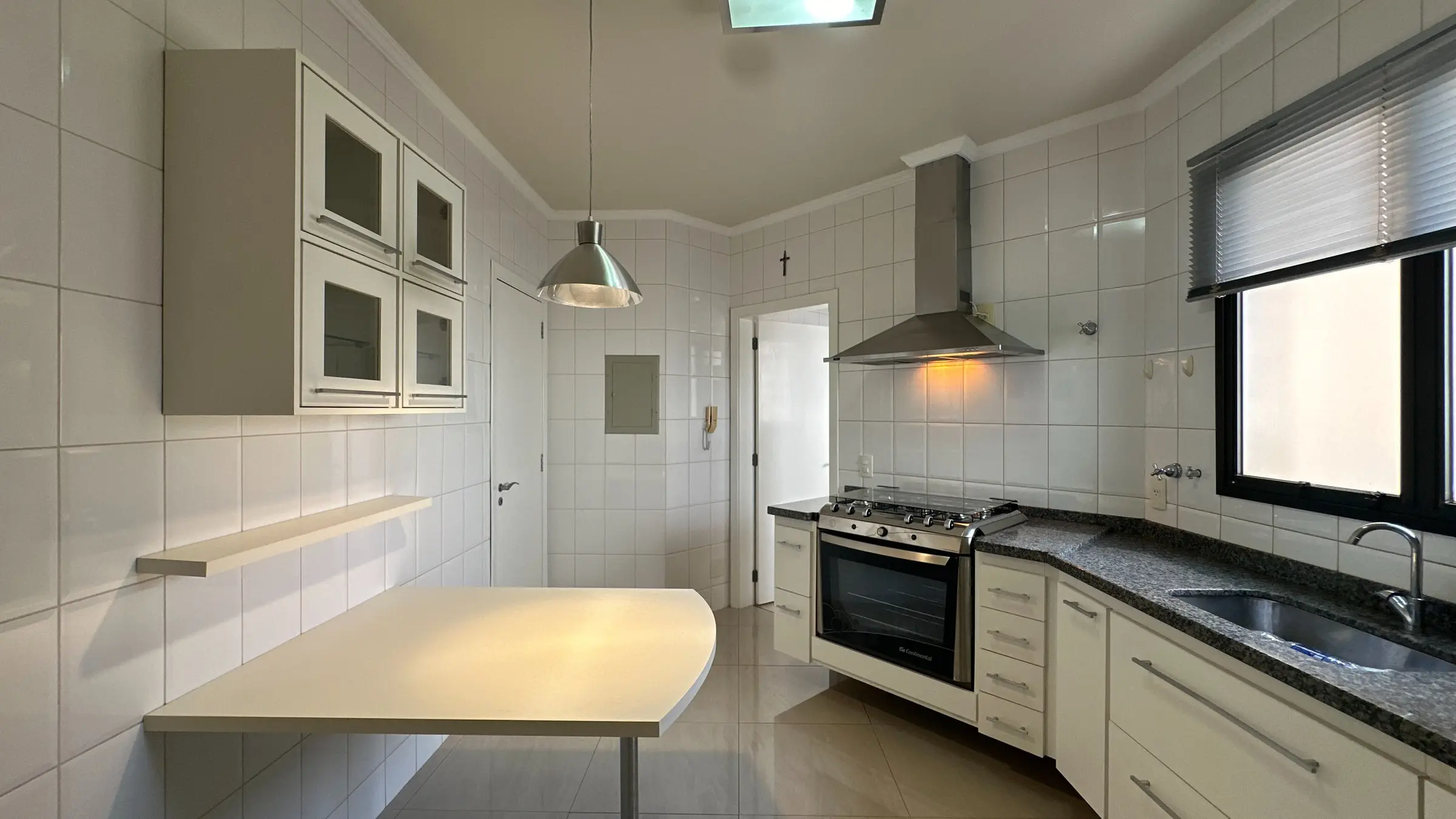 Cozinha do apartamento no Jardim Irajá, com marcenaria, cooktop, coifa e bancada em granito