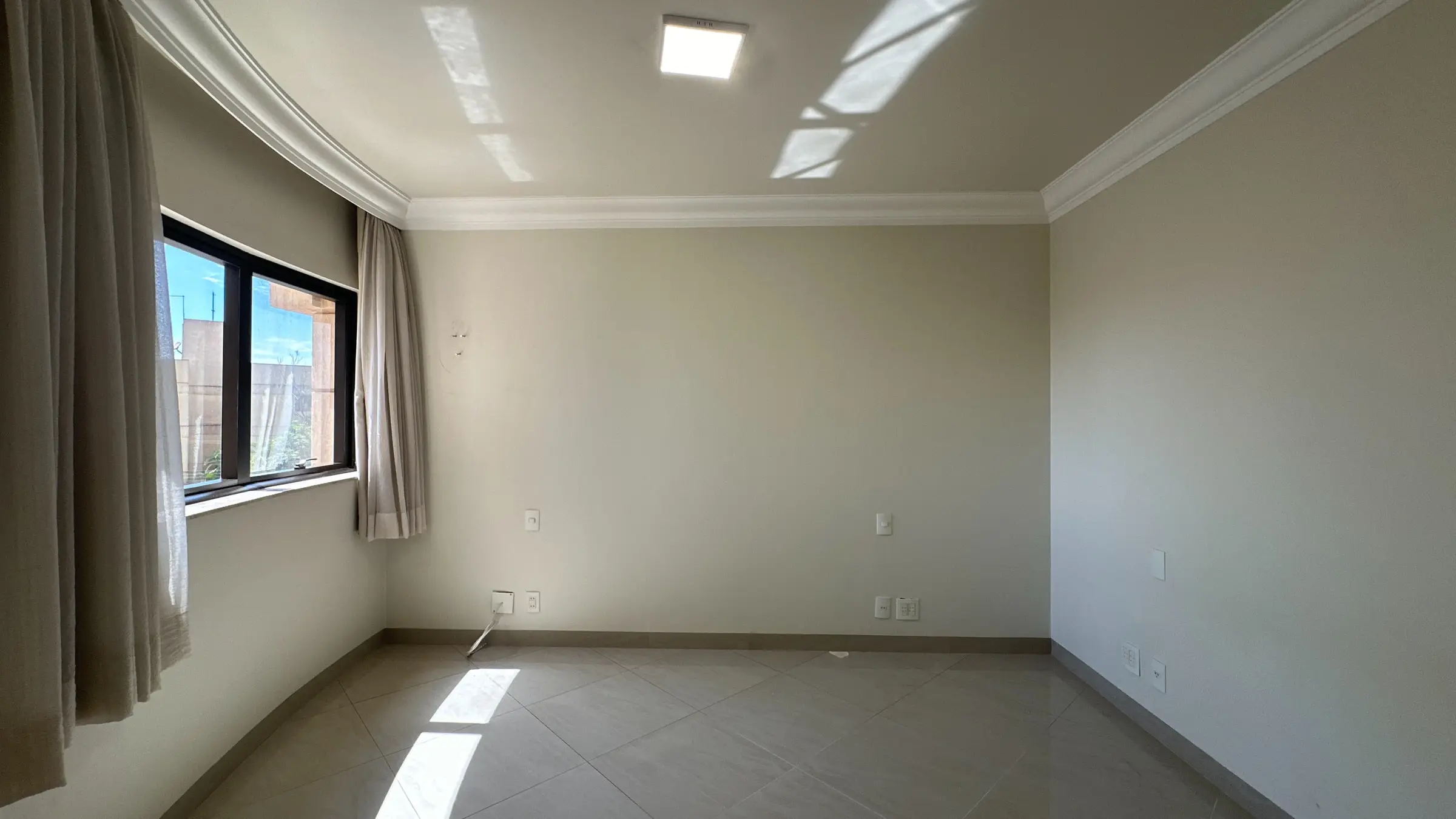 Dormitório claro do apartamento de 4 dormitórios em Ribeirão Preto, com janela ampla e cortina