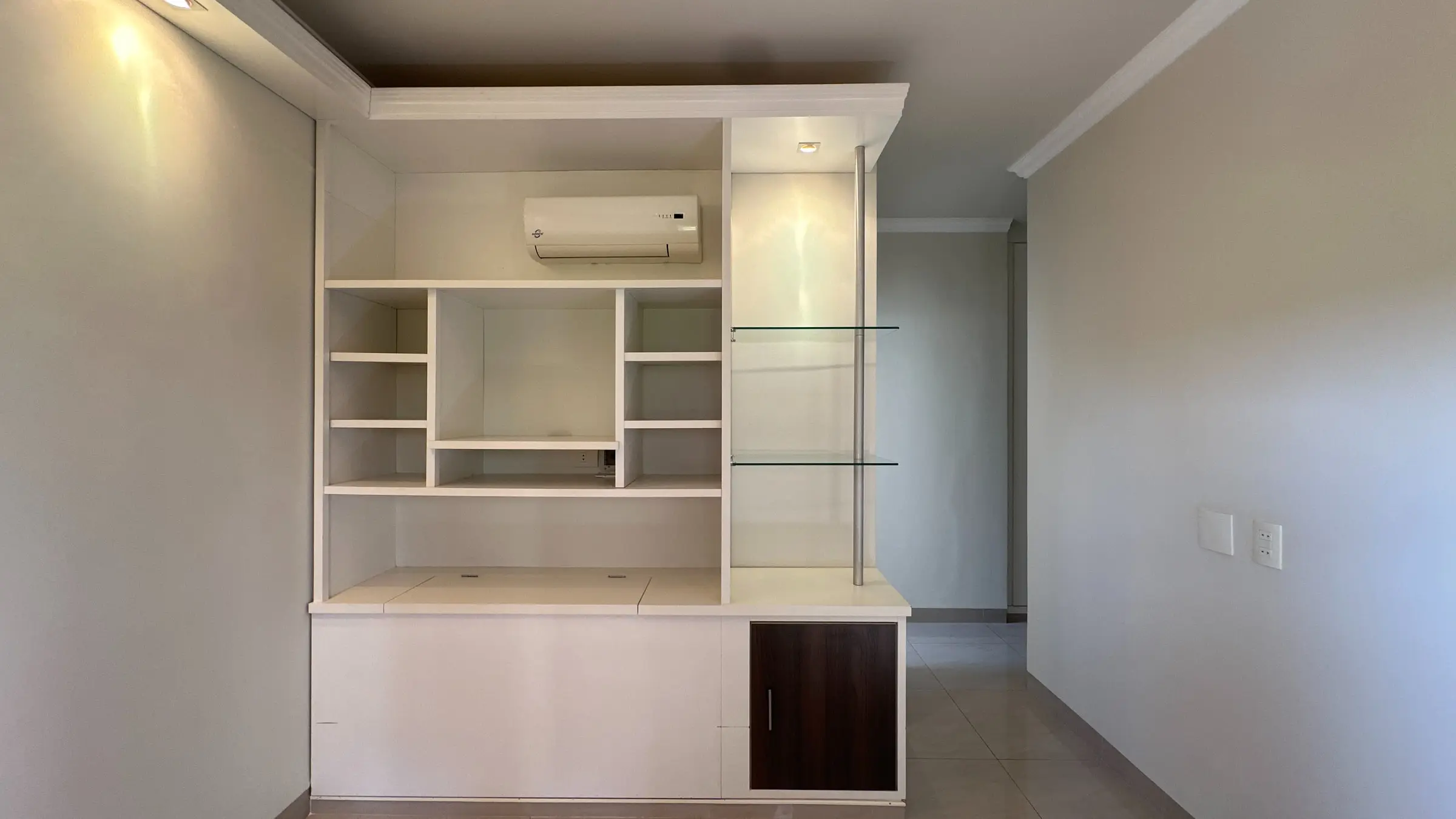 Dormitório climatizado do apartamento, com estante de marcenaria