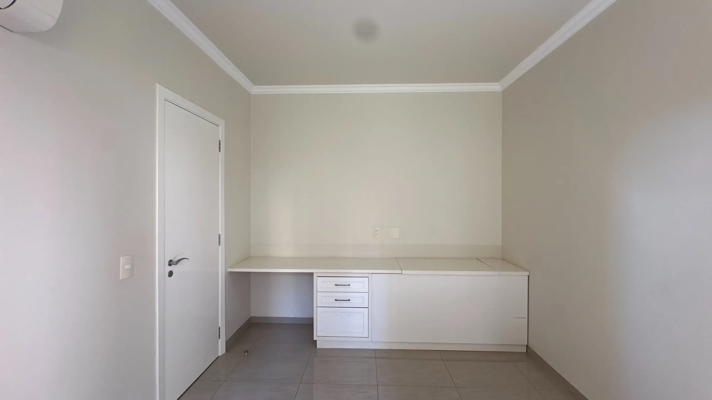 Dormitório do apartamento com bancada de estudo embutida e gavetas