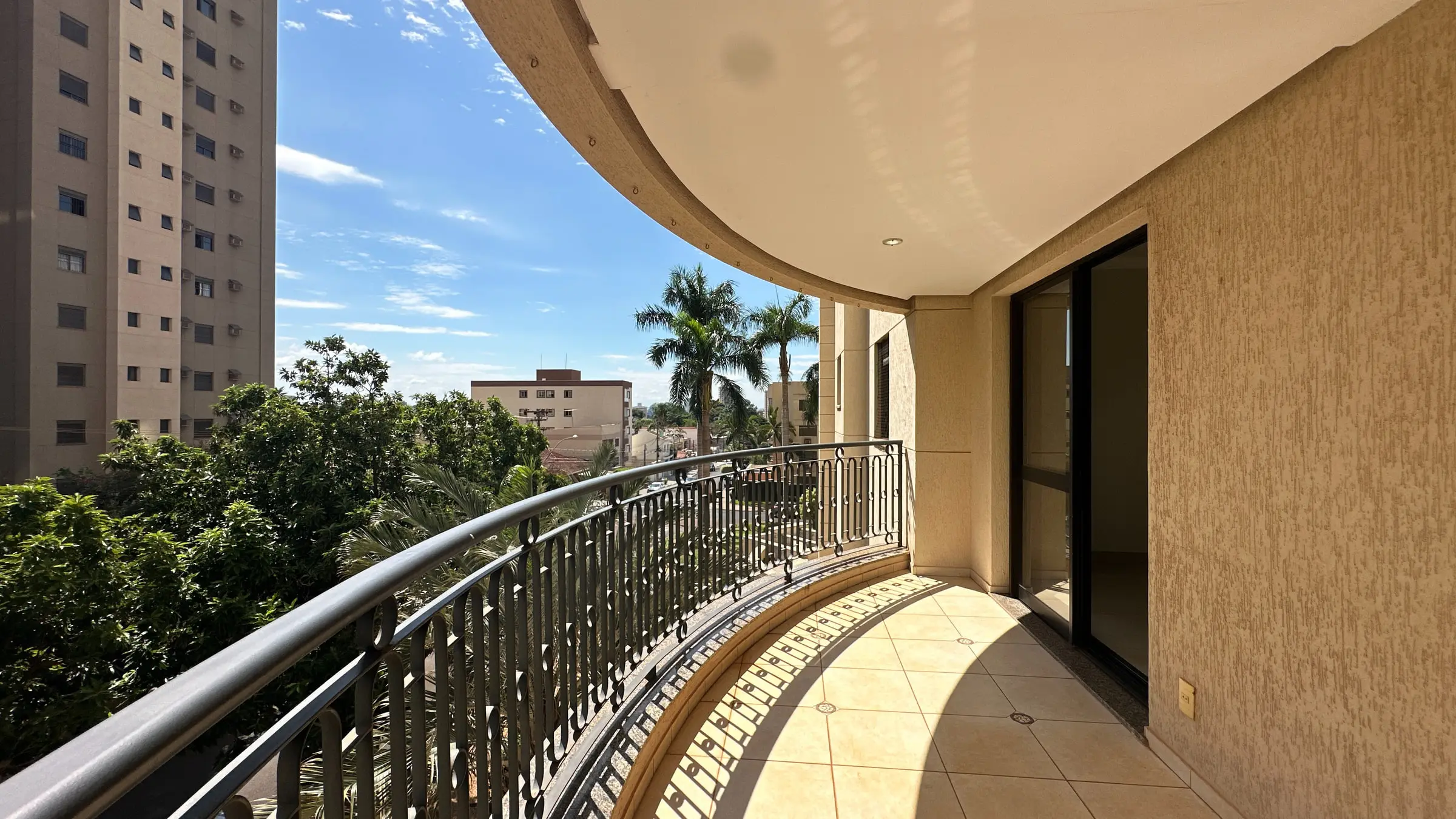 Varanda do apartamento na região da João Fiúsa com porta de acesso ao living e vista arborizada