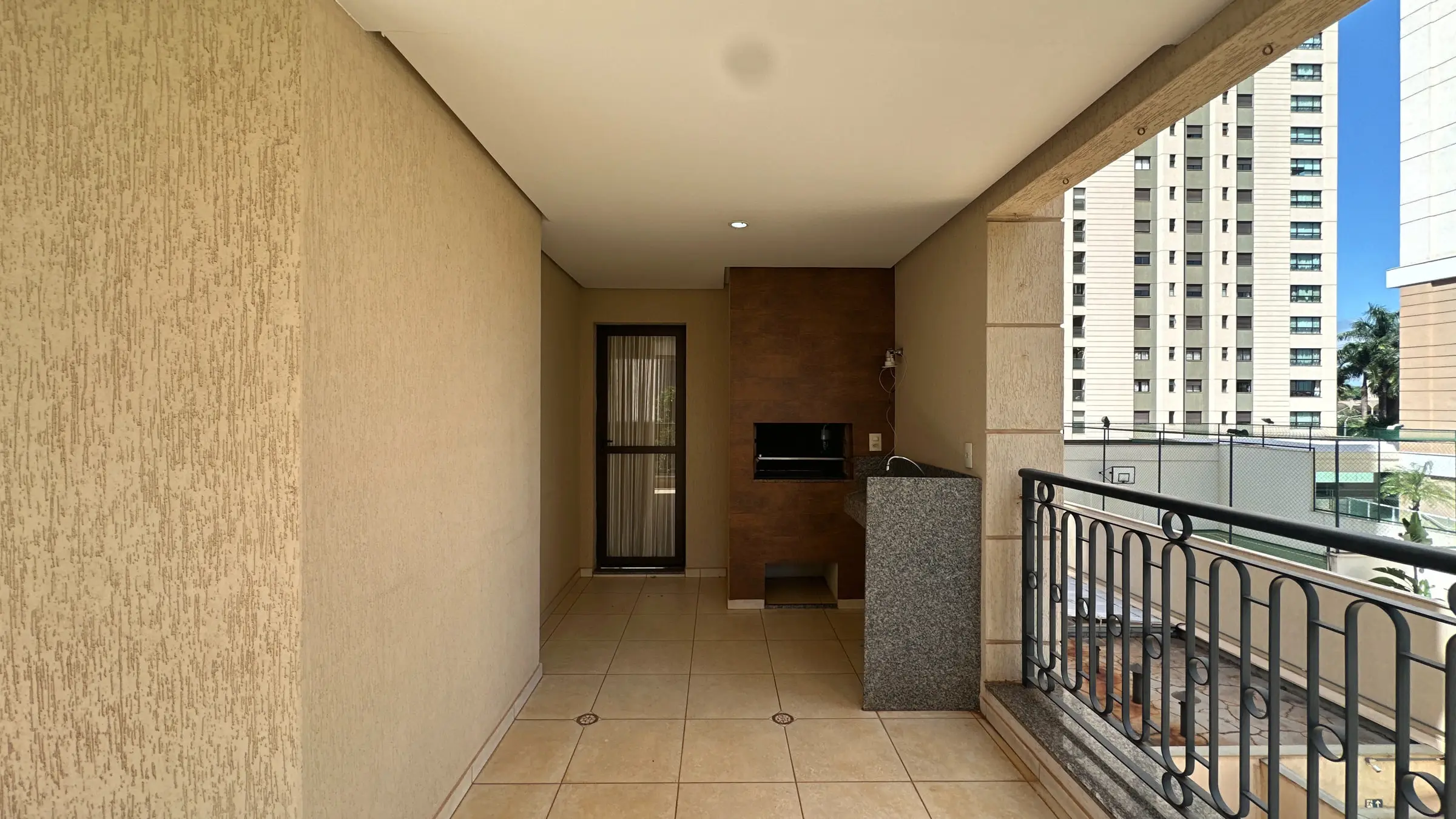 Varanda do apartamento com churrasqueira embutida e bancada em granito