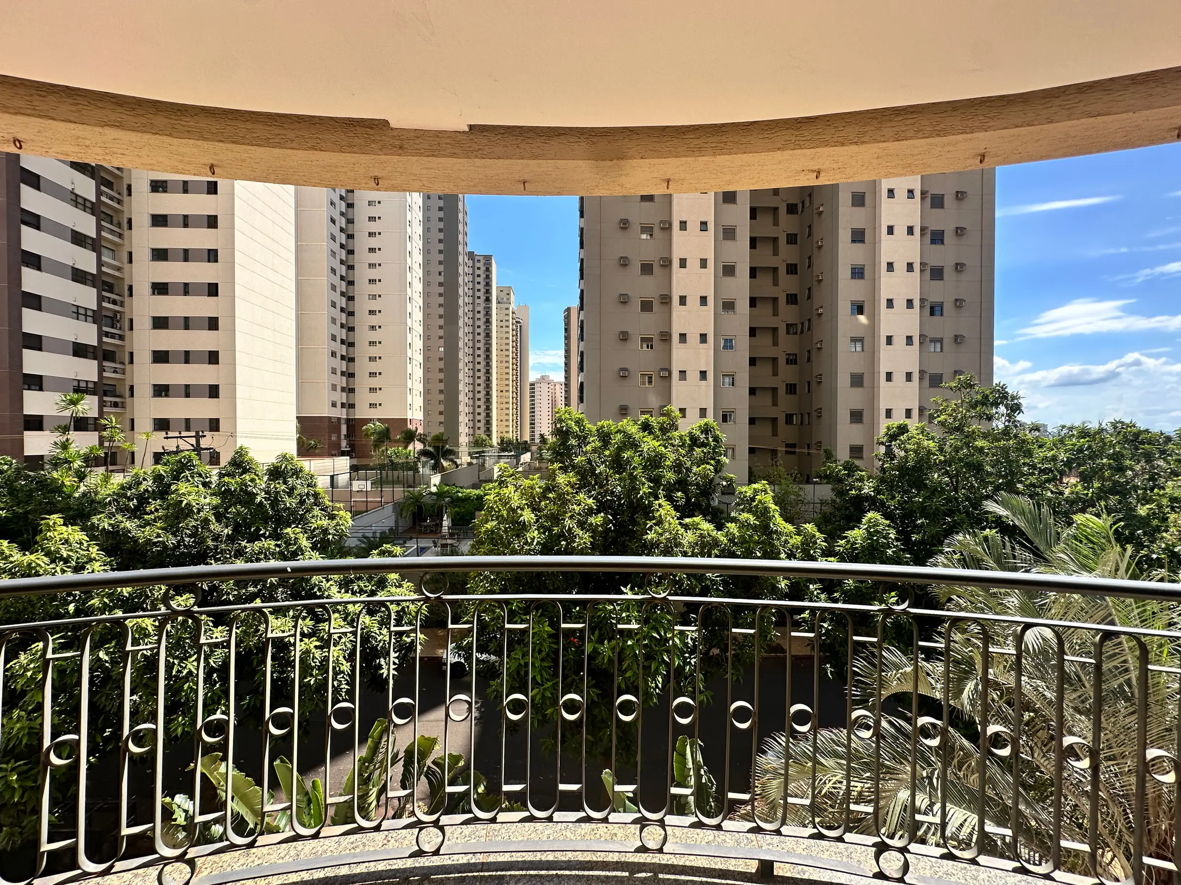 Varanda em curva do apartamento de 181 m² na região da João Fiúsa, em Ribeirão Preto, com vista para prédios e arborização
